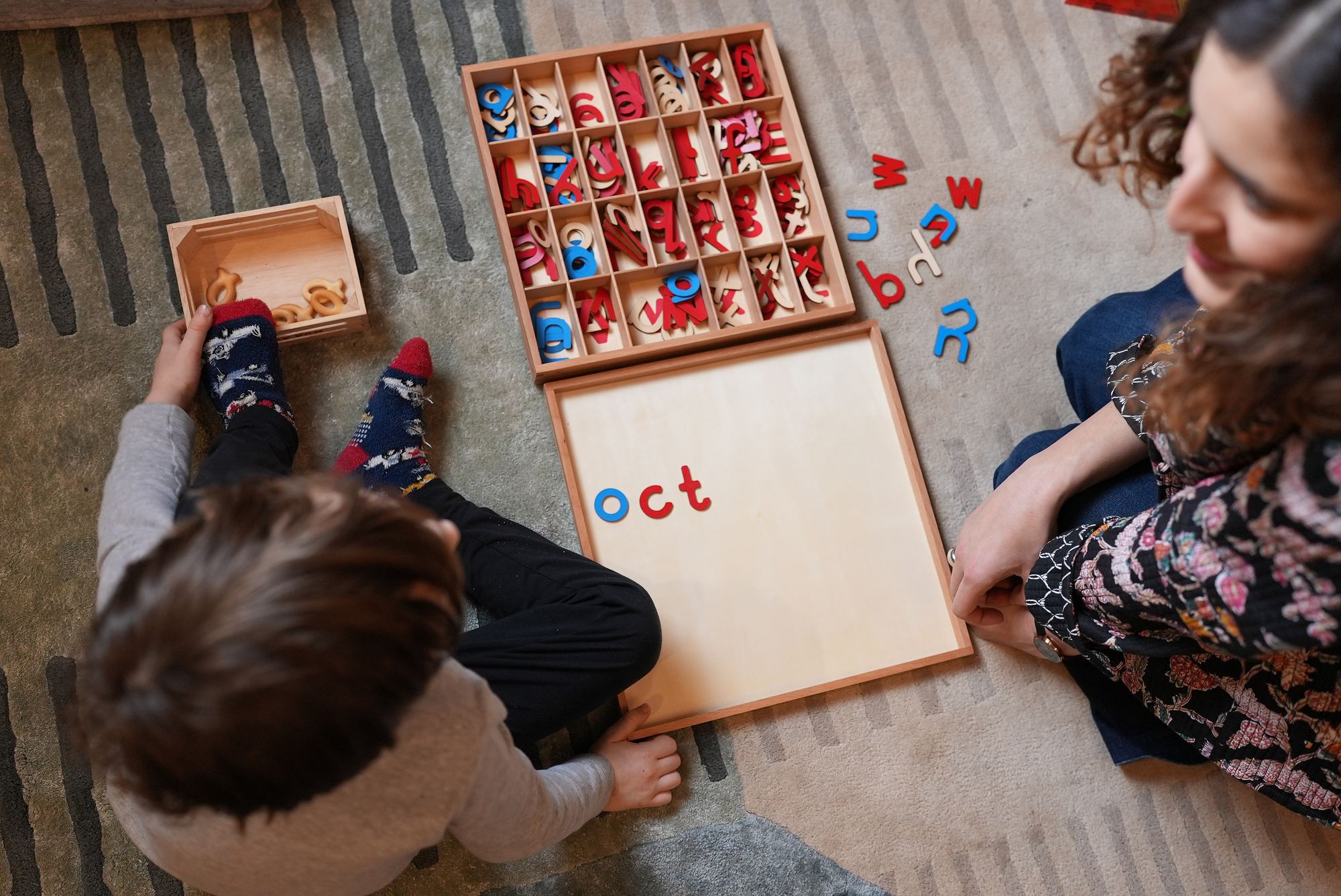 A child's hands working with the Montessori movable alphabet beside Beatrice